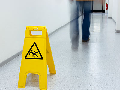 Warnschild vor rutschigem Boden in einem Flur.